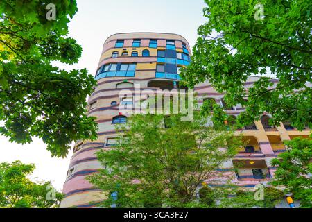 Architektonischer Blick auf den einzigartigen Wohnkomplex Waldspirale mit farbenfrohen Fassaden inmitten lebendiger Bäume in Darmstadt. Stockfoto