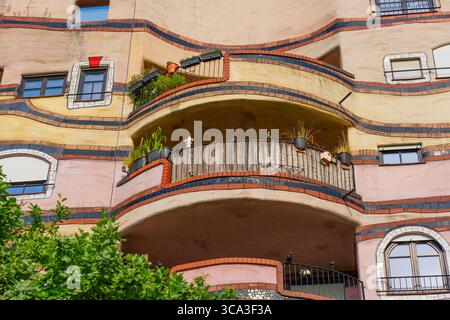 Nahaufnahme der farbenfrohen Fassade des Wohnkomplexes Waldspirale mit gewellten Balkonen, die mit Pflanzen und künstlerischen Designelementen geschmückt sind Stockfoto