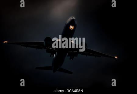 Ein Flugzeug, das am Nachthimmel mit Lichtern an Bord fliegt Stockfoto