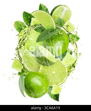 Frische Limetten und Spritzwasser in der Luft vor weißem Hintergrund Stockfoto