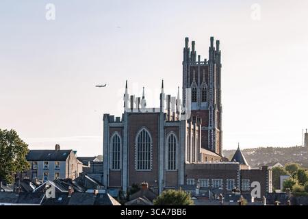 25. Juli 2025 Cork, Irland Ein großes Backsteingebäude mit einem Turm in einer belebten Stadt Stockfoto