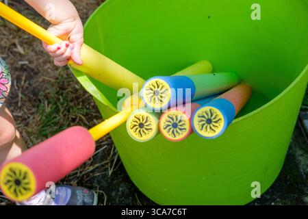 Kinder spielen im Sommer mit Wasserpistolen, Outdoor-Spielkonzept. Stockfoto