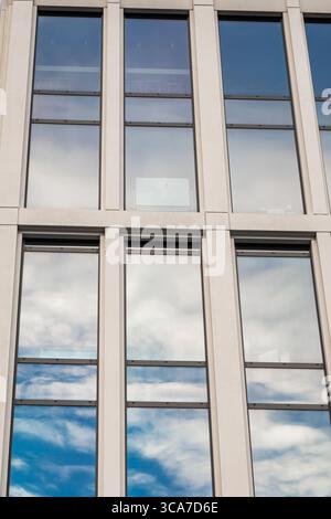 25. Juli 2025 Cork, Irland Ein Gebäude mit vielen Fenstern, die einen blauen Himmel reflektieren Stockfoto