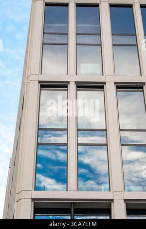 25. Juli 2025 Cork, Irland Ein hohes Gebäude mit vielen Fenstern, die den blauen Himmel reflektieren Stockfoto