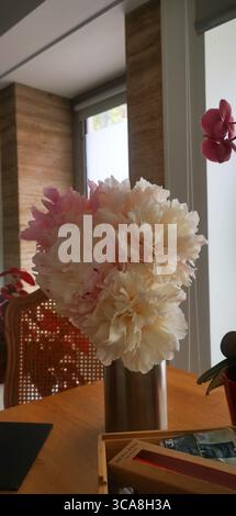 Sanfter rosa und weißer Pfingstrosenstrauß in Blüte auf einem rustikalen Holztisch - Frühlings-Wellness, natürliche Schönheit und minimalistisches Lifestyle-Konzept Stockfoto