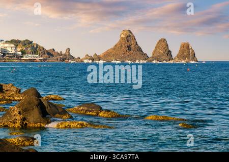 Malerische Aussicht auf den Sonnenuntergang von Acitrezza Sizilien Lavastapel und Lavasteilküsten, mit Fischerbooten im Hafen - ideal für Reisen, Kultur, Geschichte und Mittelmeer Stockfoto