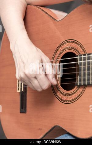 Nahaufnahme der Hände des Musikers, die eine akustische Gitarre spielen, mit Schwerpunkt auf die komplizierten Details des Instruments und die Fähigkeiten des Musikers Stockfoto