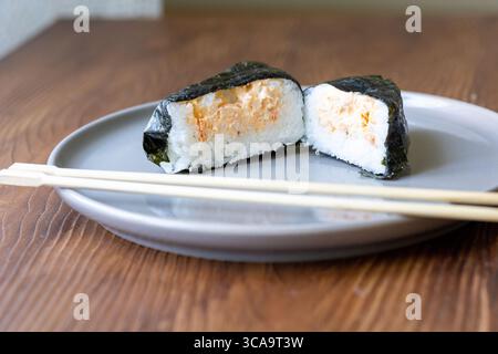 Onigiri auf einem weißen Teller auf dem Tisch in Nahaufnahme Stockfoto