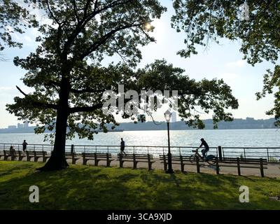 Jogger und Radfahrer auf dem Westside Radweg entlang des Hudson River mit Blick auf New Jersey im Hintergrund, Manhattan, New York City, New York, USA Stockfoto