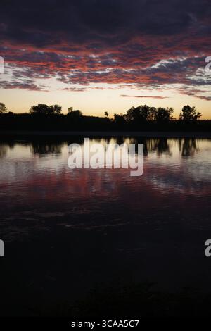 Sonnenuntergang über dem Po, Italiens längstem Fluss, mit goldenen Reflexen auf dem Wasser und einer friedlichen Atmosphäre, die die ruhige Schönheit der Natur einfängt. Stockfoto