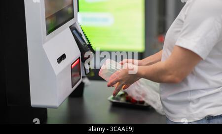 Eine Frau scannt Artikel an einer Selbstkasse. Stockfoto