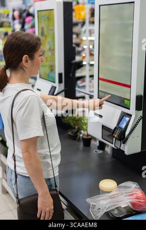 Eine Frau scannt Artikel an einer Selbstkasse. Stockfoto