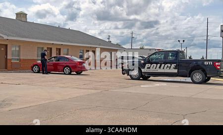 11. Mai 2023, Emporia, Kansas, USA: Der Polizeibeamte der Stadt Emporia erklärt dem Fahrer des roten BMW, warum er einen Verkehrsstopp durchführt. Der Offizier hält seine Radarkamera in der rechten Hand und zeigt sie dem Fahrer, damit der Fahrer sehen kann, wie schnell er fuhr. (Bild: © Mark Reinstein/ZUMA Press Wire) Stockfoto