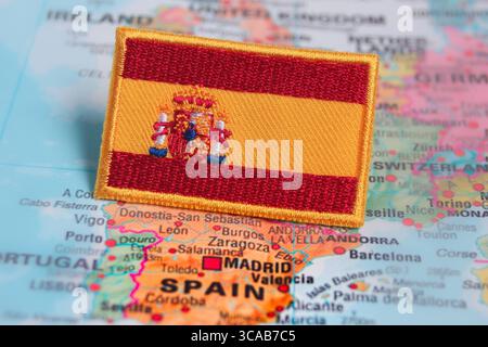 Gestickte spanische Flagge auf einer Weltkarte über Spanien, symbolisiert Patriotismus, Reiseinspirierung und umweltfreundliche Tourismuserlebnisse. Stockfoto