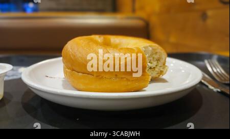 Frisch gebackener Bagel, serviert auf einem weißen Teller Stockfoto