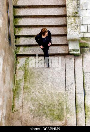 Eine Frau in schwarzem Outfit läuft eine Steintreppe hinunter. Stockfoto