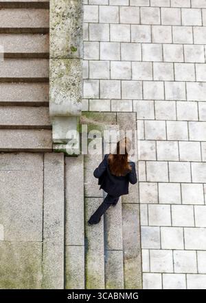 Eine Frau in einem schwarzen Anzug geht eine Treppe hinunter. Stockfoto