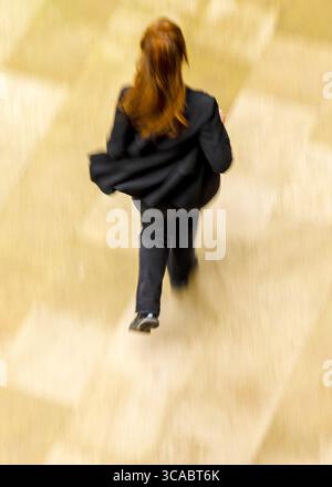 Eine Person mit langen roten Haaren läuft vor der Kamera weg. Stockfoto