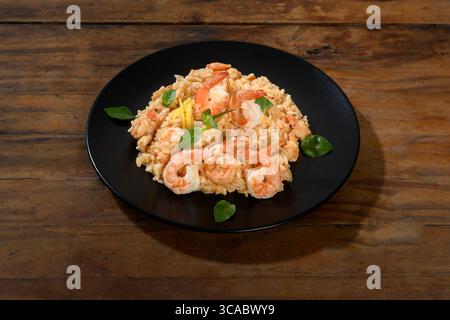 Köstliches Shrimps-Risotto serviert auf einem schwarzen Teller Stockfoto