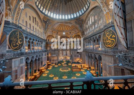Zentraler Innenblick auf die Hagia Sophia mit Kuppel, Kalligrafiemedaillons und Kronleuchtern – Istanbul, Türkei Stockfoto