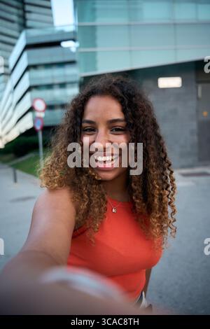Trendige junge Frau lächelt draußen auf der Straße der Stadt und strahlt Jugendliche Energie aus Stockfoto