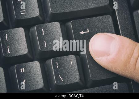 Drücken Sie mit dem Finger die EINGABETASTE der Tastatur. Nahaufnahme und getöntes Bild Stockfoto
