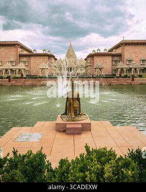 Robbinsville, NJ - USA - 2. August 2025 der ruhige Brahm Kund, ein traditioneller Stufenteich. Eine goldene kniende Statue und tanzende Springbrunnen zieren die Vorderseite Stockfoto