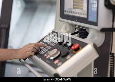 Bediener an der Steuerung der CNC-Metallbearbeitungsmaschine. Selektiver Fokus. Stockfoto