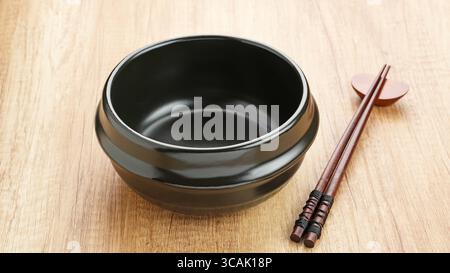 Traditioneller koreanischer Tontopf Ttukbaegi auf Holztisch Stockfoto
