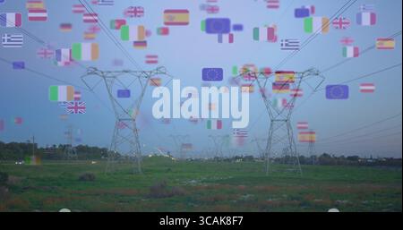 Mit Stahlgittertürmen, die in der Dämmerung Stromleitungen über das Grasland tragen, mit europäischen Flaggen Stockfoto