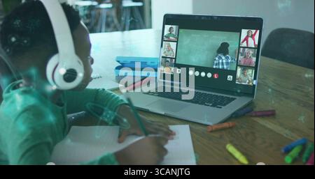 Schreibender Junge mit Kopfhörern, Notizen im Arbeitsbereich, mit Laptop und Buntstiften, Kopierraum Stockfoto