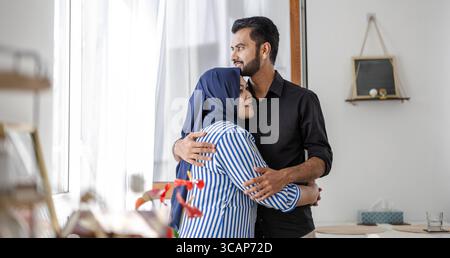 Ein liebevolles muslimisches Paar, das im Wohnzimmer ihres Hauses steht Stockfoto