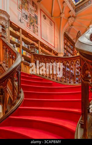 Wendeltreppe mit rotem Teppichboden und kunstvollen hölzernen Bücherregalen im historischen Lello Buchladen Porto, geschwungene Treppen, literarisches Wahrzeichen, Portugiesisch Stockfoto
