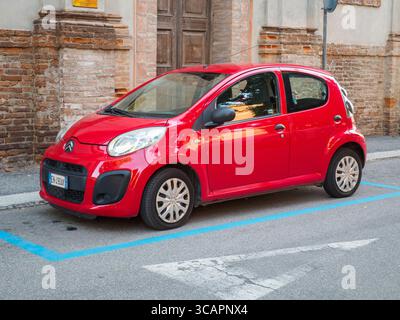 Cremona, Italien 4. August 2025 hellroter Citroen C1 Stadtauto parkt auf einem markierten Parkplatz auf einer gepflasterten Straße neben einem alten Backsteingebäude mit einem Stockfoto