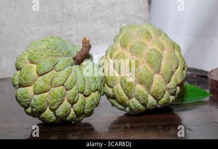 Zucker Apfel oder Pudding Apfel ( annona squamosa ) grünes Blatt auf hölzernem Hintergrund , gesunde Früchte Stockfoto
