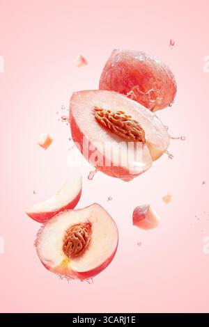Saftige Pfirsichscheiben in Bewegung mit Wasserspritzern auf rosa Hintergrund, Pfirsichscheiben mit Wasserspritzern isoliert auf rosa Hintergrund Stockfoto