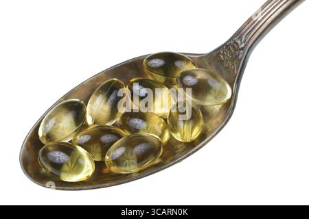 Im alten goldenen Löffel befindet sich ein kleiner Haufen gelber Pillen mit Omega-Vitaminen. Isoliert auf weißem Studio-Makro Stockfoto
