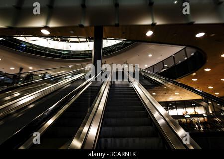 Beleuchteter Flughafen Zürich mit Eskalator in unscharfer Bewegung bei Nacht im Flughafen Kloten, Zürich, Kanton Zürich, Schweiz Stockfoto