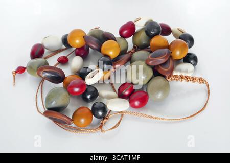 Hausgemachte weibliche Perlen bestehen aus mehrfarbigen glatten, polierten Steinen und Glas . Weißer Hintergrund Stockfoto