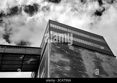 Ein auffälliges Schwarz-weiß-Foto eines modernen Industriegebäudes, das ein einzigartiges architektonisches Design mit großen Fenstern und einer strukturierten Kontur zeigt Stockfoto