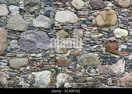 Wand aus grobem Granit kleinen und großen Steinen. Natürlichen Hintergrund Stockfoto