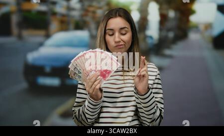 Frau, die isländische Krone draußen hält, mit einem nachdenklichen Ausdruck auf einem Stadtstraßenhintergrund. Stockfoto