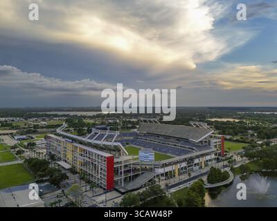 Orlando, USA - 21. Juli 2025: Die lebhafte Fassade des Camping World Stadions aus der Vogelperspektive steht im Kontrast zum ruhigen See unter einem Himmel mit dramatischen Wolken. Stockfoto