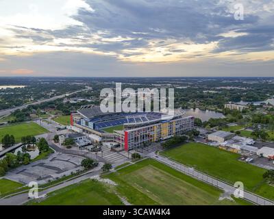 Orlando, Vereinigte Staaten - 21. Juli 2025: Aus der Vogelperspektive das Camping World Stadium, das sich in einer sanften Dämmerung erfreut. Seine lebhafte Fassade steht im Kontrast zum üppigen Grün und der fernen Stadtlandschaft. Stockfoto