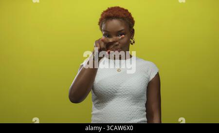 Junge afroamerikanische Frau, die vor gelbem Studiohintergrund mit dem Finger auf die Kamera zeigt; Selbstvertrauen. Stockfoto