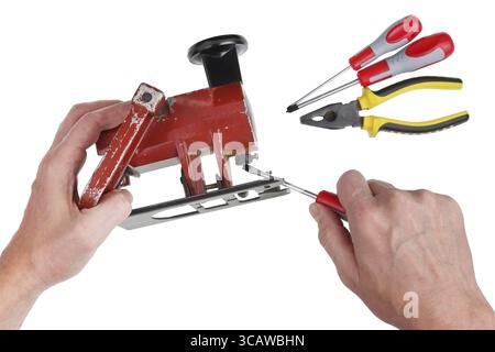 Ein alter alter alter Meister versucht, eine kaputte elektrische Stichsäge im Retro-Stil zu reparieren. Isoliert auf weißem Draufsicht-Studio Stockfoto