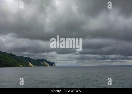 Graue Wolken über einer Küste mit grünen Klippen und ruhigem Wasser. Der Blick auf die Ostsee vom Pier 18586 Sellin, Insel Rügen Stockfoto