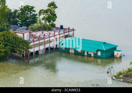 Sariakandi, Bangladesch - 15. Juli 2019: Aus der Vogelperspektive von Gebäuden, die in Hochwasser getaucht sind, spiegelt einen starken Kontrast zwischen den Strukturen und dem umgebenden Wasser wider. Stockfoto