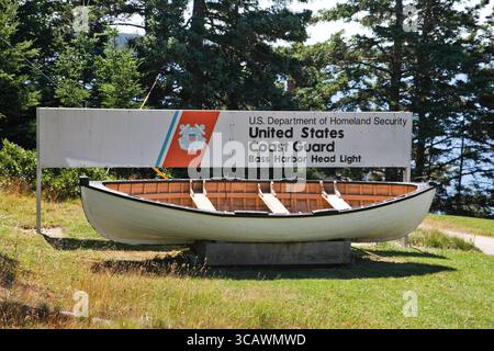 BASS HARBOR, MAINE, USA - 7. AUGUST 2010: Ein Holzboot unter einem Schild für die US-Küstenwache am Bass Harbor Head Light. Stockfoto