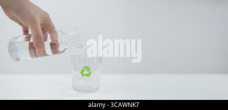 Eine Hand gießt sauberes Wasser aus einer transparenten Flasche in ein Glas und symbolisiert damit Nachhaltigkeit, Umweltschutz und die Bedeutung von reinem, gefiltertem Wasser Stockfoto
